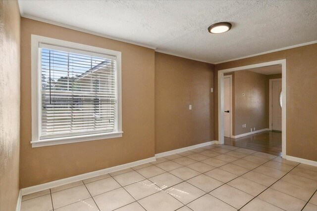 unfurnished room featuring a textured ceiling, ornamental molding, and light tile patterned flooring