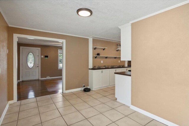 tiled foyer featuring ornamental molding and a textured ceiling