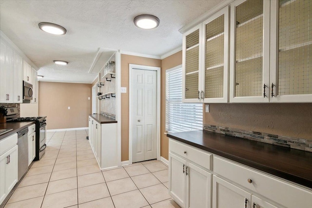 kitchen with crown molding, white cabinets, light tile patterned floors, and appliances with stainless steel finishes