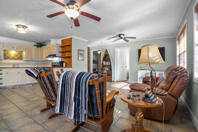 tiled living room featuring ceiling fan, ornamental molding, and a textured ceiling