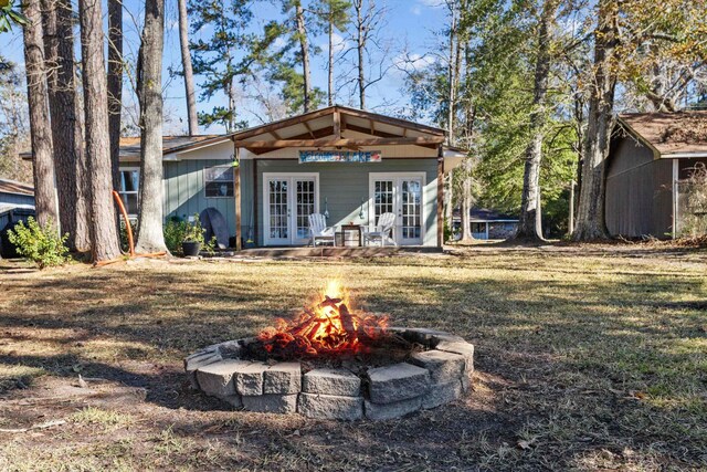 rear view of house featuring a lawn, french doors, and a fire pit