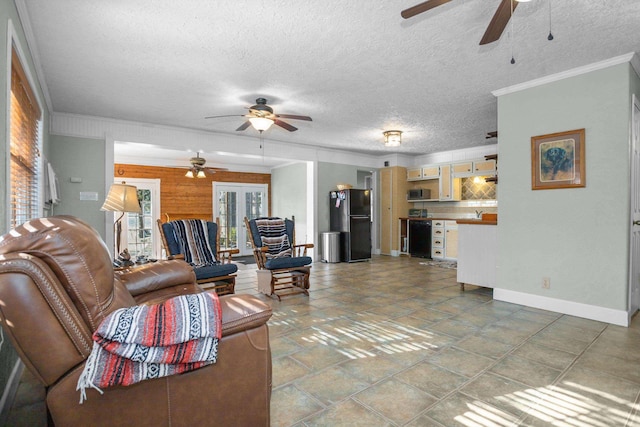 living room featuring french doors, a textured ceiling, crown molding, and wood walls