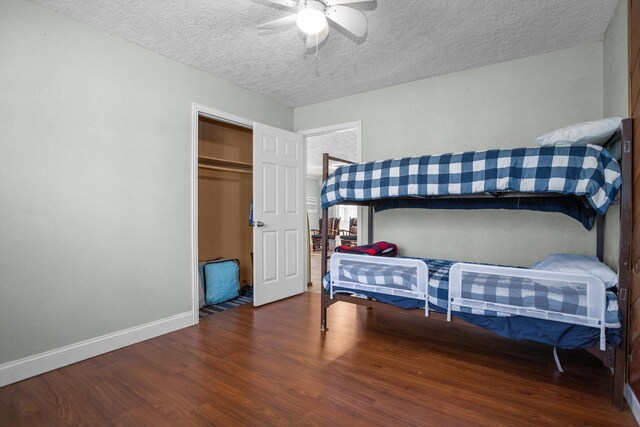 bedroom featuring a textured ceiling, dark hardwood / wood-style flooring, a closet, and ceiling fan