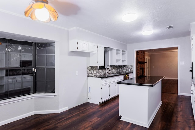 kitchen featuring sink, white cabinetry, tasteful backsplash, a kitchen island, and dark hardwood / wood-style flooring