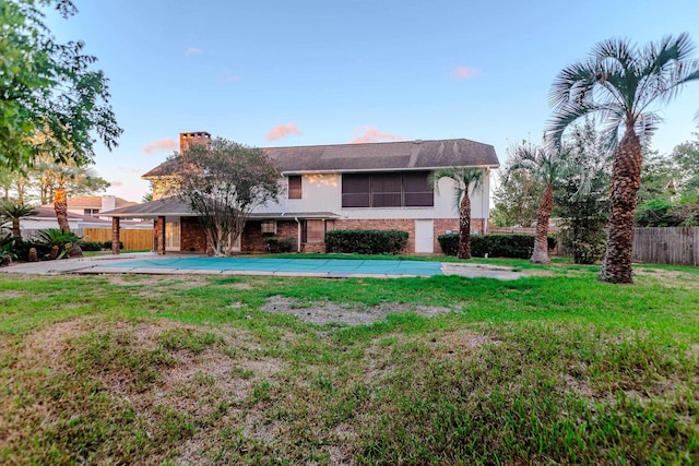 rear view of property featuring a yard and a covered pool