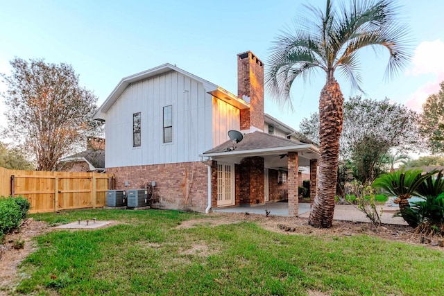 rear view of property featuring a yard, a patio area, and central air condition unit