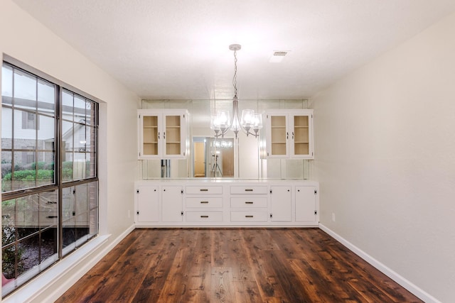 unfurnished dining area featuring dark hardwood / wood-style floors, a chandelier, and a textured ceiling