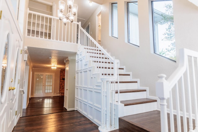 stairway with an inviting chandelier, a towering ceiling, and hardwood / wood-style floors