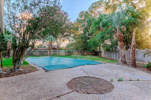 pool at dusk with a patio area