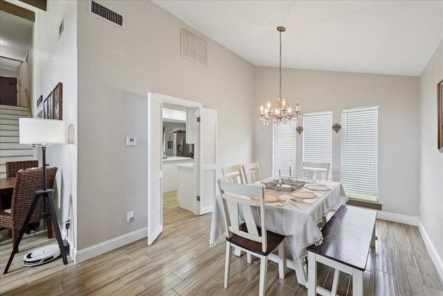 5955 Bicentennial Ln, Beaumont, TX 77706 - dining room with vaulted ceiling, light wood-style flooring, a chandelier, and stairs