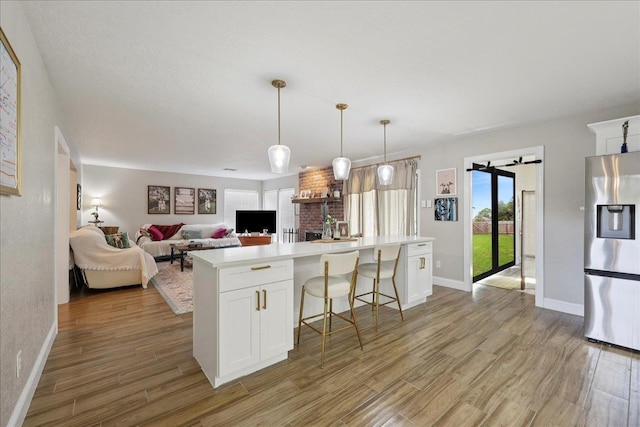 5955 Bicentennial Ln, Beaumont, TX 77706 - kitchen featuring stainless steel fridge, light wood-style flooring, white cabinetry, light countertops, and a center island