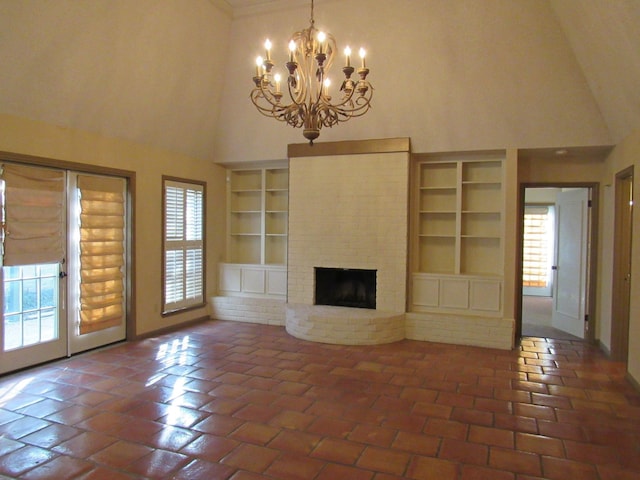 unfurnished living room with a notable chandelier, a high ceiling, a fireplace, baseboards, and built in features