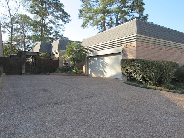 view of side of property featuring a garage, a shingled roof, mansard roof, and brick siding