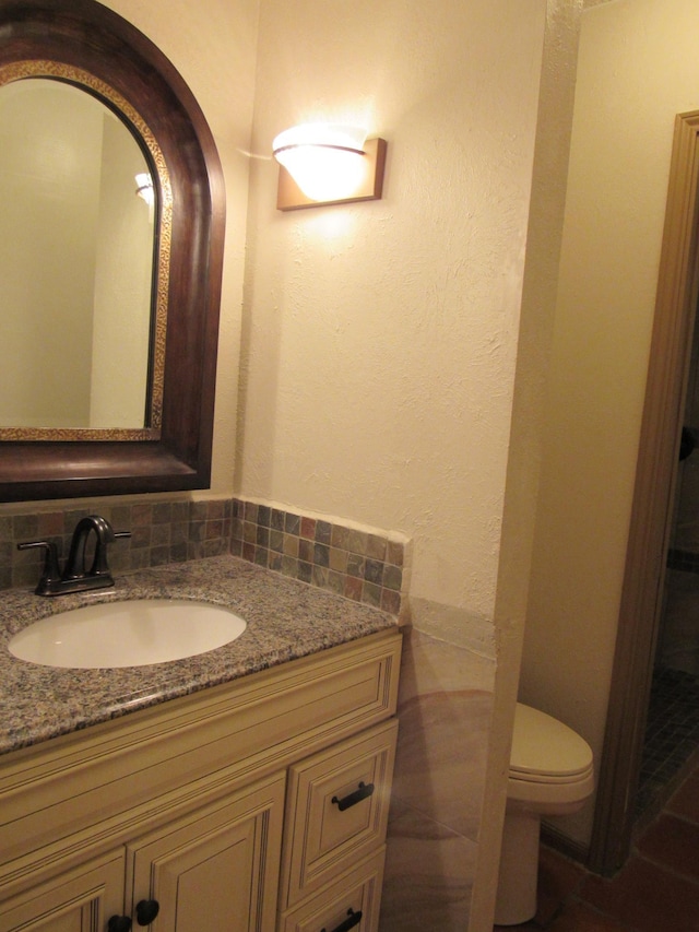 bathroom featuring toilet, backsplash, and vanity