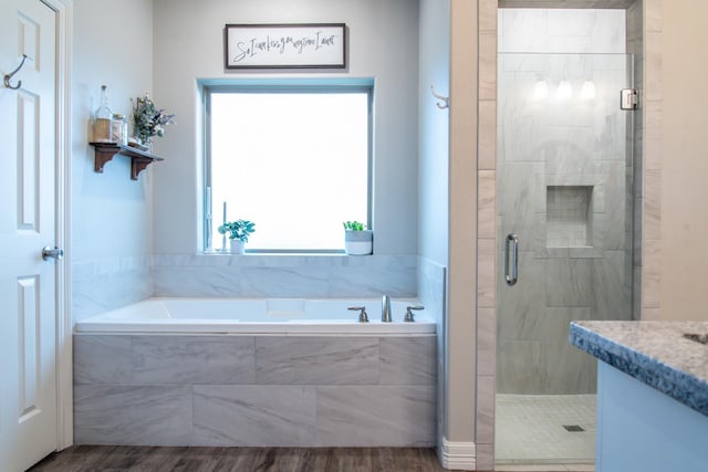 bathroom with wood-type flooring, vanity, and plus walk in shower