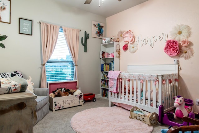 carpeted bedroom featuring a nursery area and ceiling fan