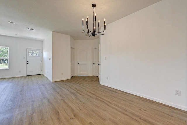 unfurnished dining area with a chandelier and light wood-type flooring