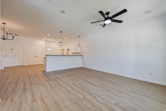 unfurnished living room with light hardwood / wood-style flooring, ceiling fan with notable chandelier, and sink