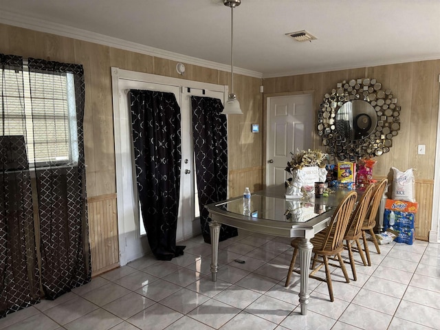 dining area featuring crown molding, wood walls, light tile patterned flooring, and visible vents