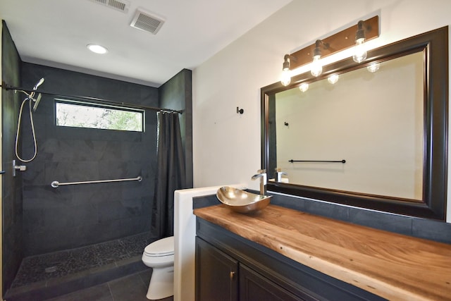 bathroom featuring vanity, visible vents, a tile shower, tile patterned floors, and toilet