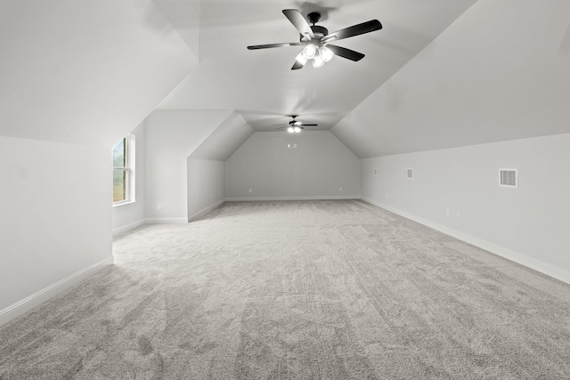 additional living space with lofted ceiling, visible vents, light carpet, ceiling fan, and baseboards