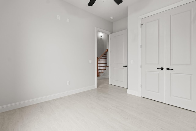 unfurnished bedroom with ceiling fan, a closet, light wood-style flooring, and baseboards