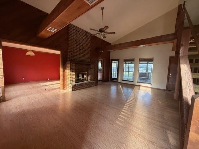 unfurnished living room featuring high vaulted ceiling, a ceiling fan, wood finished floors, a brick fireplace, and visible vents