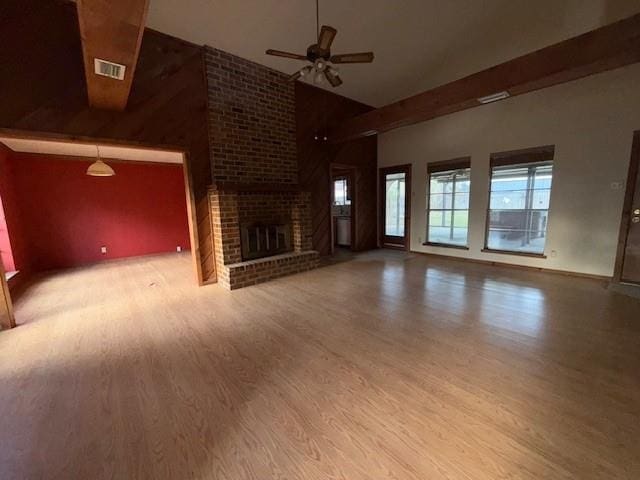 unfurnished living room featuring high vaulted ceiling, visible vents, a ceiling fan, a fireplace, and wood finished floors