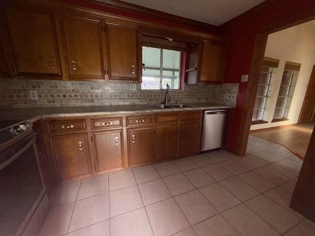 kitchen with tasteful backsplash, range, a sink, light tile patterned flooring, and dishwasher