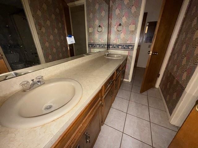 full bathroom with a sink, double vanity, wallpapered walls, and tile patterned floors