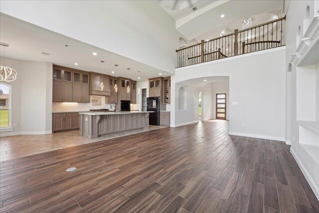 3730 Loblolly Trl, Beaumont, TX 77713 - unfurnished living room with a towering ceiling, dark wood-style floors, a ceiling fan, arched walkways, and baseboards
