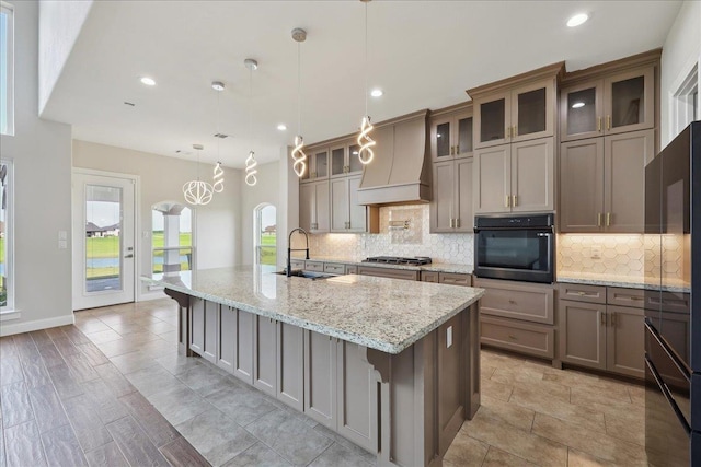 3730 Loblolly Trl, Beaumont, TX 77713 - kitchen with black oven, a sink, custom exhaust hood, backsplash, and a spacious island