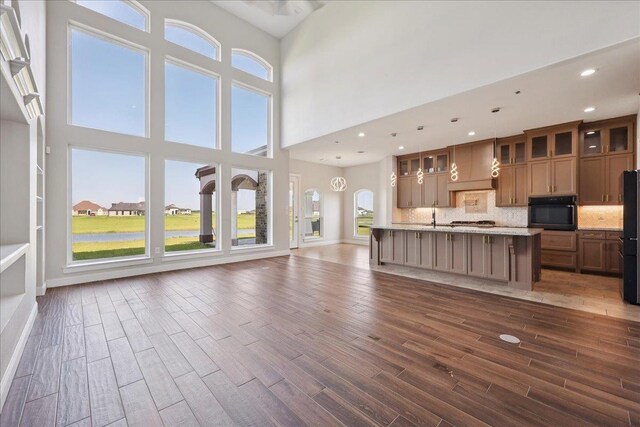 3730 Loblolly Trl, Beaumont, TX 77713 - kitchen with gas stovetop, a kitchen island with sink, glass insert cabinets, recessed lighting, and light stone countertops