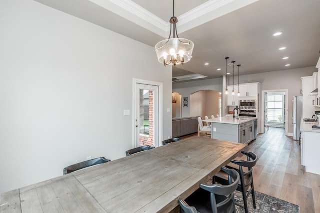 4813 Augusta Dr, Groves, TX 77619 - dining area featuring arched walkways, crown molding, recessed lighting, light wood-style flooring, and a chandelier