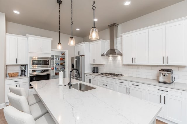 4813 Augusta Dr, Groves, TX 77619 - kitchen featuring appliances with stainless steel finishes, wall chimney range hood, an island with sink, decorative backsplash, and a breakfast bar area