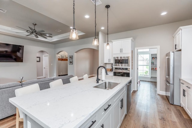 4813 Augusta Dr, Groves, TX 77619 - kitchen featuring appliances with stainless steel finishes, open floor plan, arched walkways, recessed lighting, and light wood-type flooring