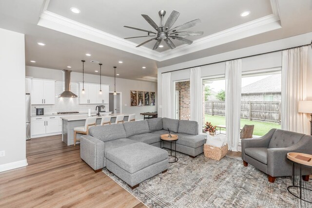 4813 Augusta Dr, Groves, TX 77619 - living room featuring a tray ceiling, ornamental molding, a ceiling fan, light wood-style flooring, and recessed lighting
