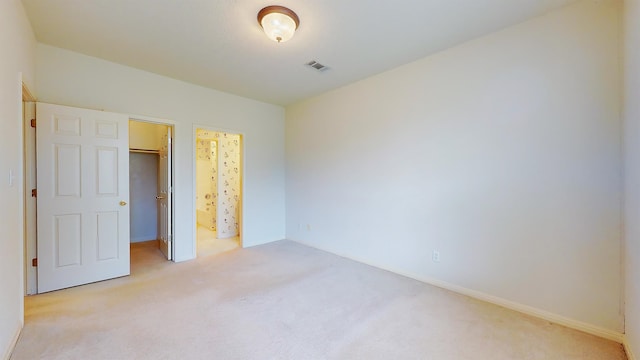 unfurnished bedroom featuring light carpet, visible vents, a walk in closet, and a closet