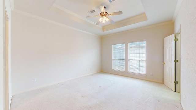 spare room with light carpet, visible vents, baseboards, ornamental molding, and a raised ceiling