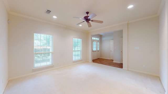 unfurnished room with a wealth of natural light, carpet, visible vents, and crown molding