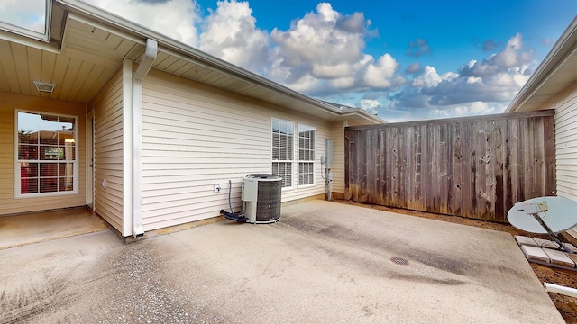 view of side of home with fence, central AC unit, and a patio