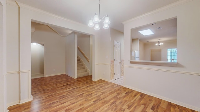 spare room with crown molding, light wood finished floors, visible vents, stairway, and an inviting chandelier