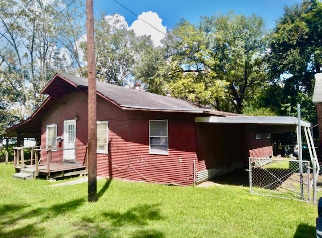 rear view of property with a lawn, a wooden deck, and a carport