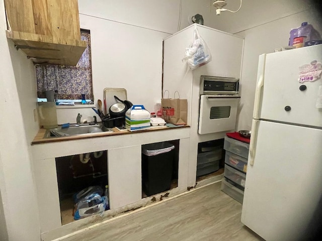 kitchen featuring sink, white appliances, and light wood-type flooring