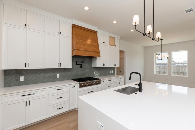 3580 Lily Ln, Beaumont, TX 77713 - kitchen featuring a sink, a chandelier, stainless steel gas stovetop, custom exhaust hood, and backsplash