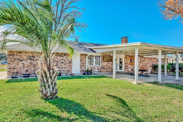 845 Flicker St, Bridge City, TX 77611 - rear view of house featuring brick siding, a yard, and a chimney