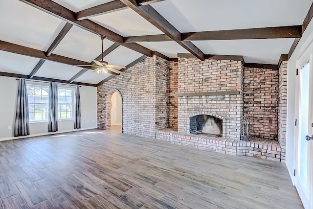 845 Flicker St, Bridge City, TX 77611 - unfurnished living room featuring brick wall, a ceiling fan, arched walkways, wood finished floors, and a brick fireplace