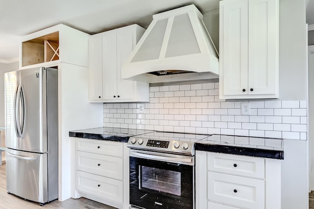 kitchen featuring white cabinets, decorative backsplash, premium range hood, and appliances with stainless steel finishes