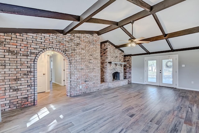 unfurnished living room featuring french doors, a brick fireplace, brick wall, ceiling fan, and lofted ceiling