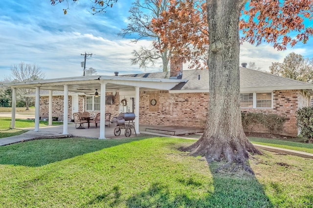 rear view of property featuring ceiling fan and a lawn